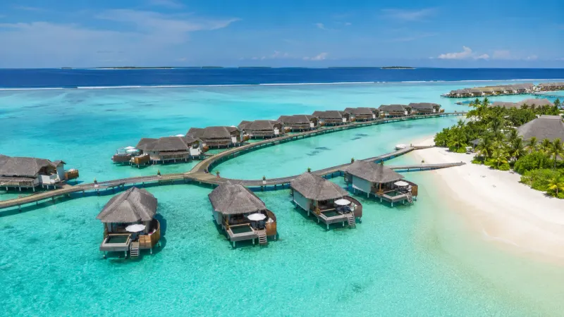 Adults-only overwater bungalow resort in the Maldives with crystal lagoon and white sand beach, sold by Piccola Travel, a Miami travel agency.