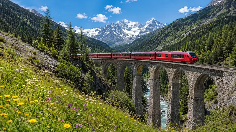 A red alpine train crossing a stone viaduct in the Swiss Alps