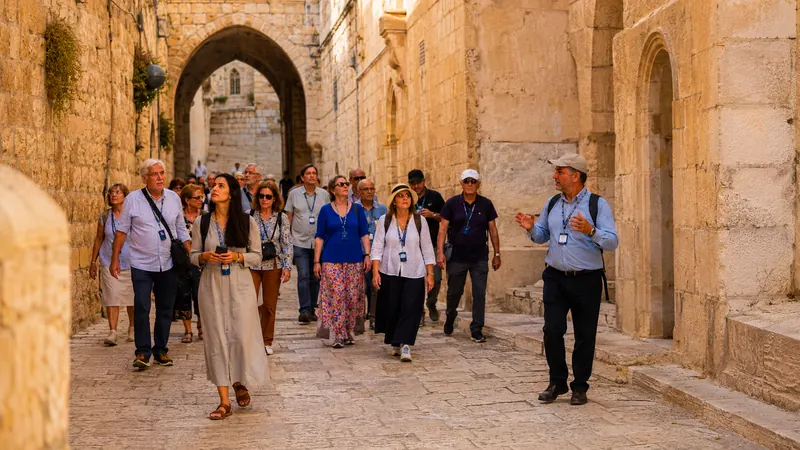 Pilgrimage group walking with a guide through the ancient stone streets of Jerusalem's Old City on a Holy Land tour organized by Piccola Travel, a Florida travel agency.