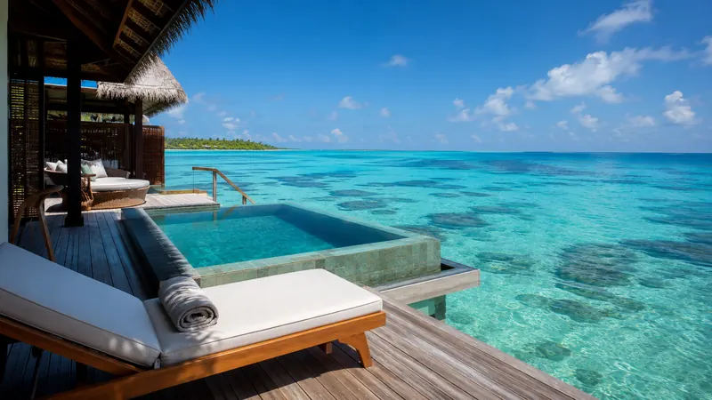 Overwater villa suite with private plunge pool over a turquoise Maldives lagoon, luxury stay planned by Piccola Travel, a Miami travel agency.