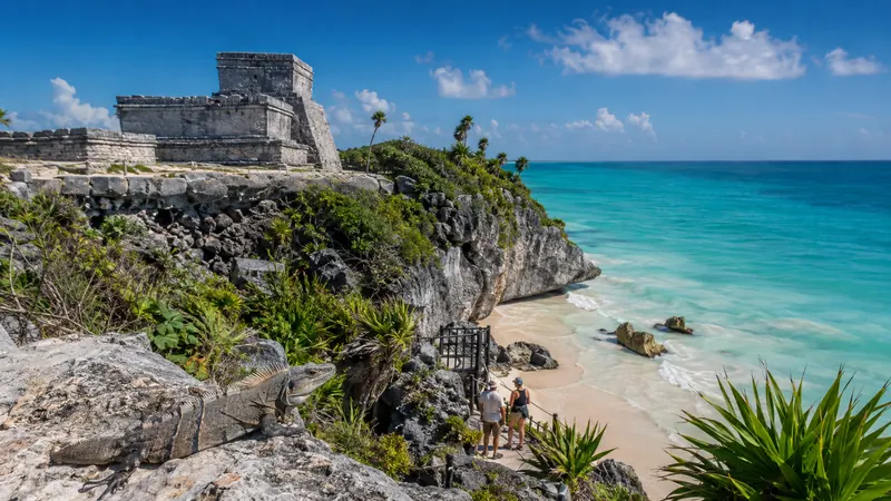 The Tulum Mayan ruins on a cliff above a turquoise cove on a Riviera Maya tour