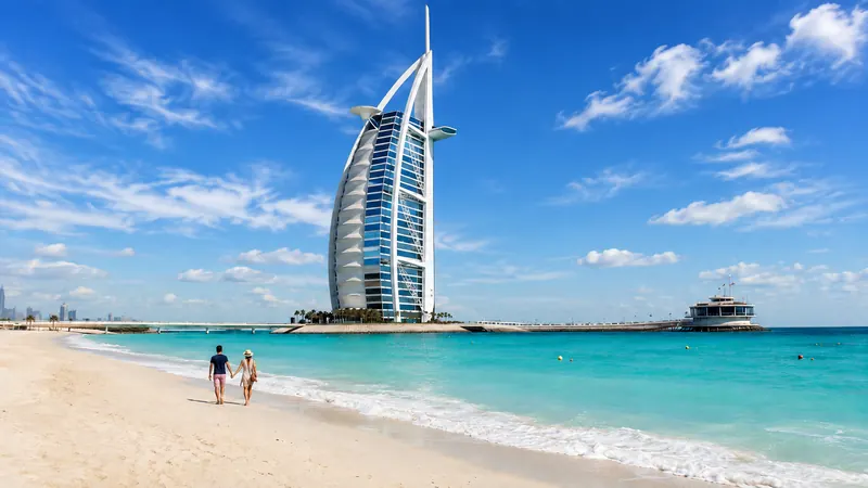 Couple strolling the beach at the sail-shaped Burj Al Arab hotel — Burj Al Arab Dubai.
