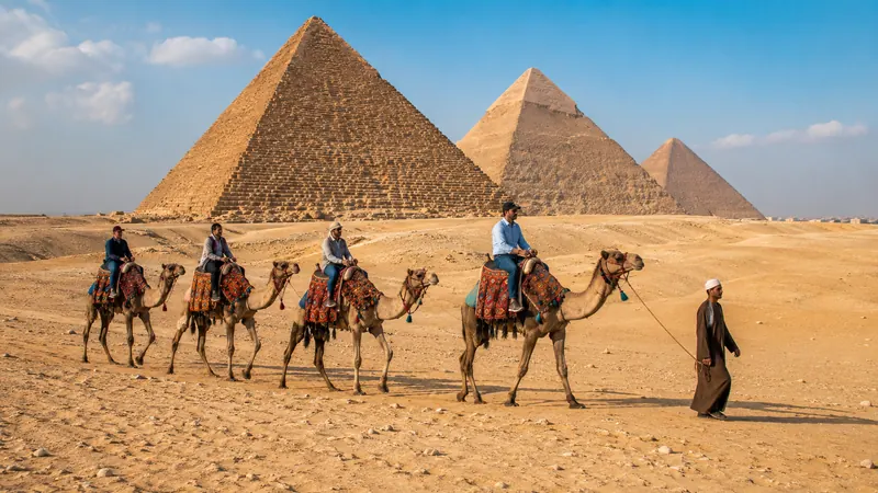 Camel caravan crossing the desert before the Great Pyramids of Giza — Giza pyramids camel ride.