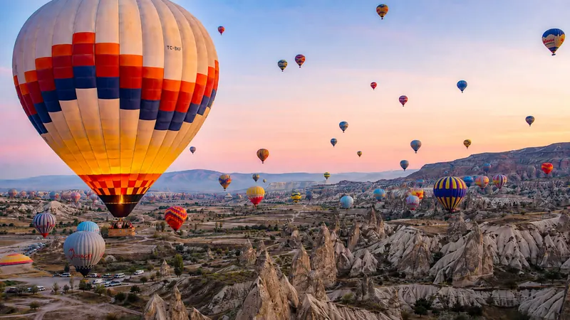 Hot air balloons drifting over Cappadocia's fairy chimneys at sunrise — Cappadocia hot air balloon ride.