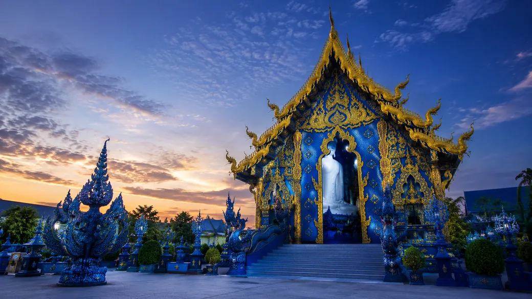 The sapphire-blue facade and golden details of the Blue Temple, Wat Rong Suea Ten, in Chiang Rai at dusk