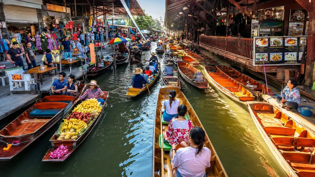 Wooden boats piled with tropical fruit at the Damnoen Saduak floating market on a Thailand vacation