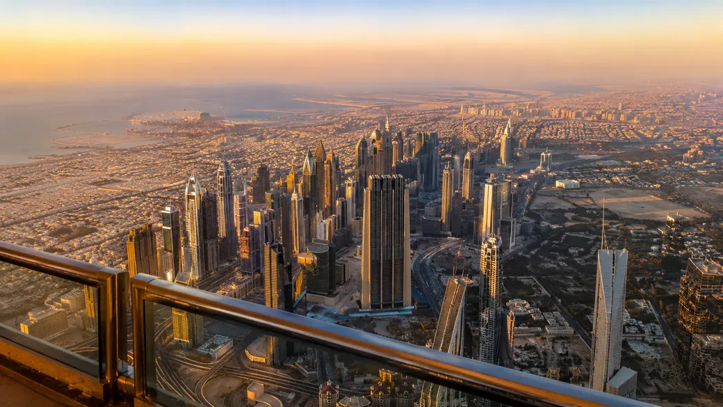 Sweeping view of Dubai's towers and coastline from the Burj Khalifa observation deck at golden hour