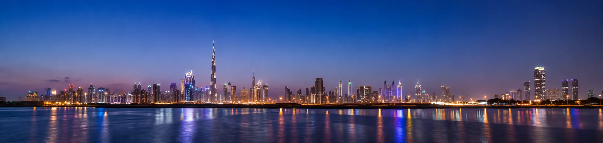 The Dubai skyline glowing at blue hour above calm water on a New Year's celebration trip
