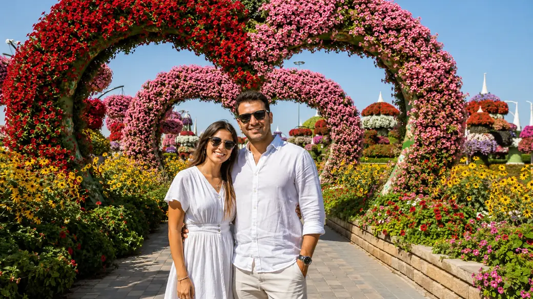 Couple posing under vibrant flower arches on a garden park walkway during a guided Dubai vacation trip