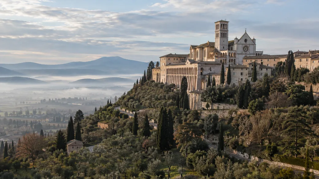 The Basilica of St. Francis on its hilltop in Assisi above the misty Umbrian valley