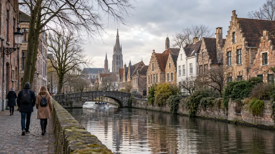 A Bruges canal lined with stepped-gable brick houses under a stone bridge