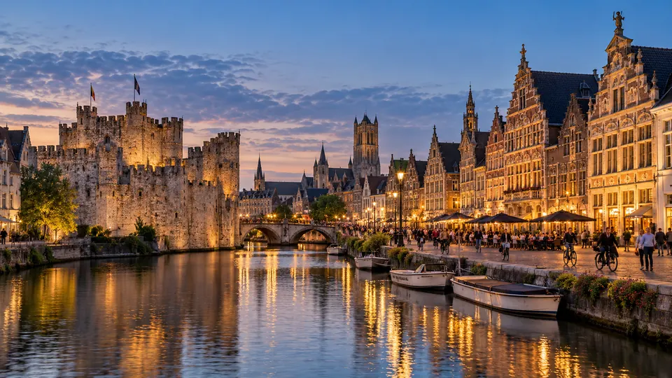 The Gravensteen castle and the lit guild houses of the Graslei in Ghent at dusk