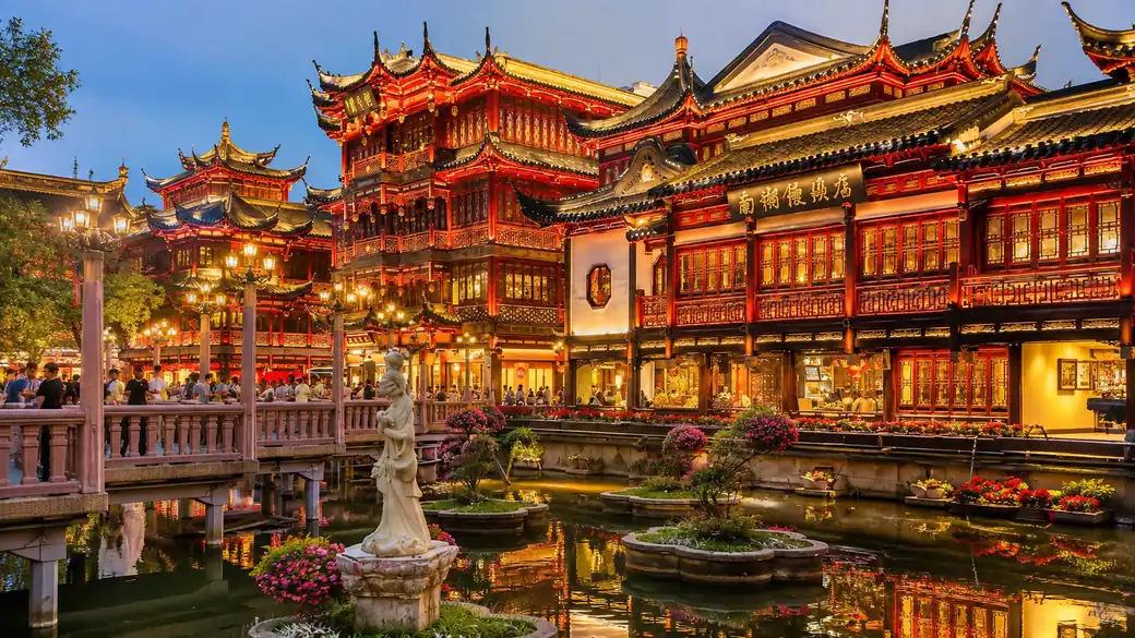 Illuminated pavilions of the Yuyuan Garden bazaar at dusk in Shanghai, a classic stop on a China tour