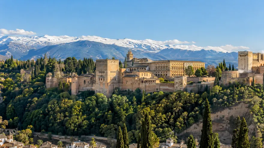 The Alhambra on its hill with the snow-capped Sierra Nevada behind, in sunlight