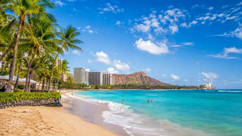 Waikiki Beach palms and turquoise surf beneath Diamond Head in Hawaii — Hawaii beach vacation packages.