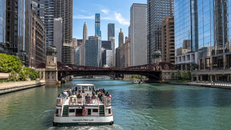 Architecture cruise boat on the Chicago River between skyscrapers — US city and culture tours.